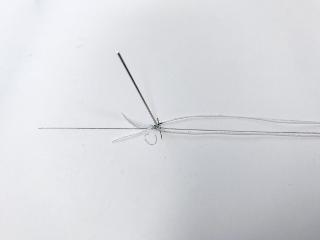 The prepared string is pulled through the pivot pin.