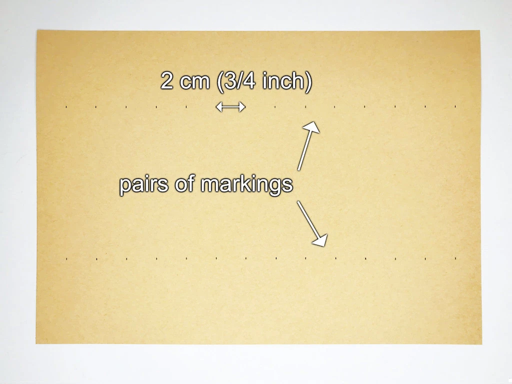 Pairs of markings drawn on an A4 kraft paper that will create lines of future pleats.