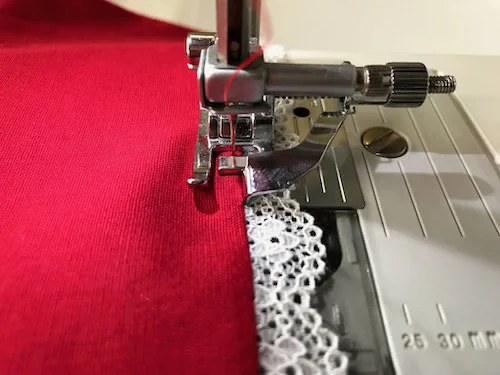 Topstitching fabric with attached lace trim using a blind-stitch presser foot.