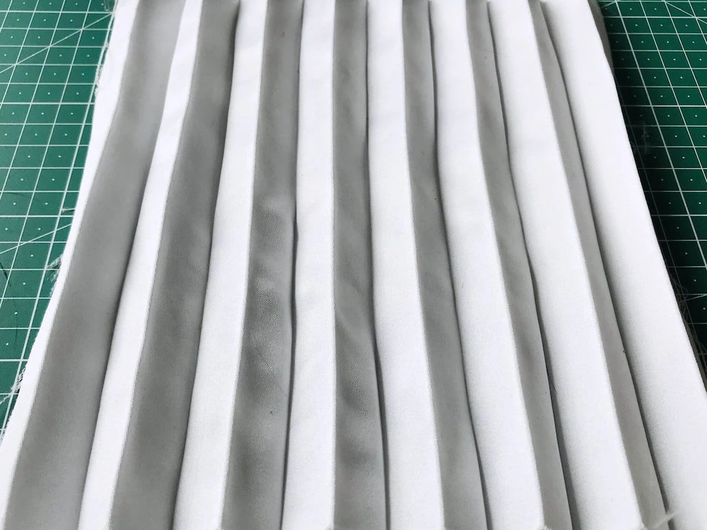 Creased permanently pleated duchess satin fabric. Permanent accordion pleats.