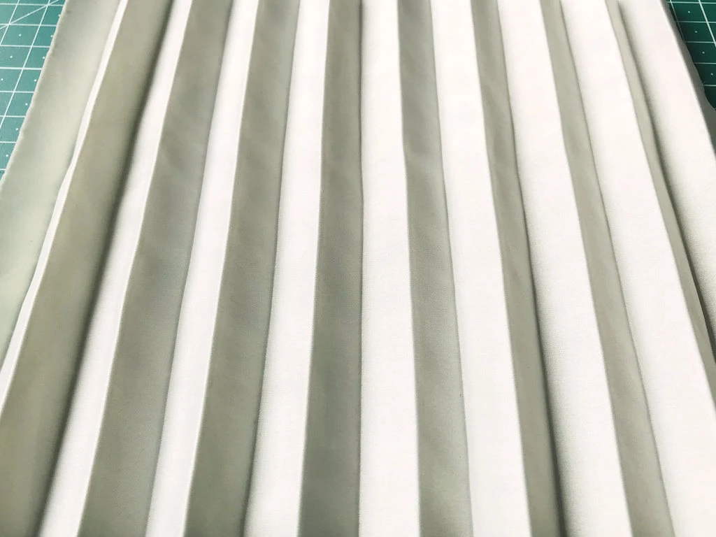 Creased permanently pleated micro satin fabric. Permanent accordion pleats.