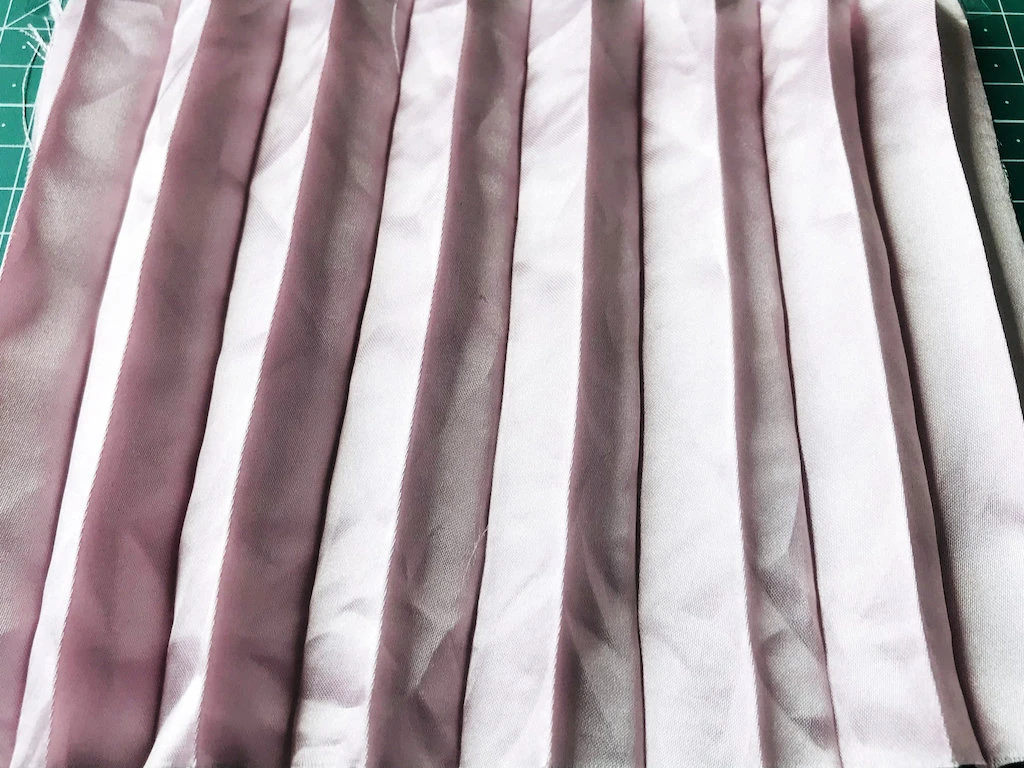 Creased permanently pleated satin fabric. Permanent accordion pleats.