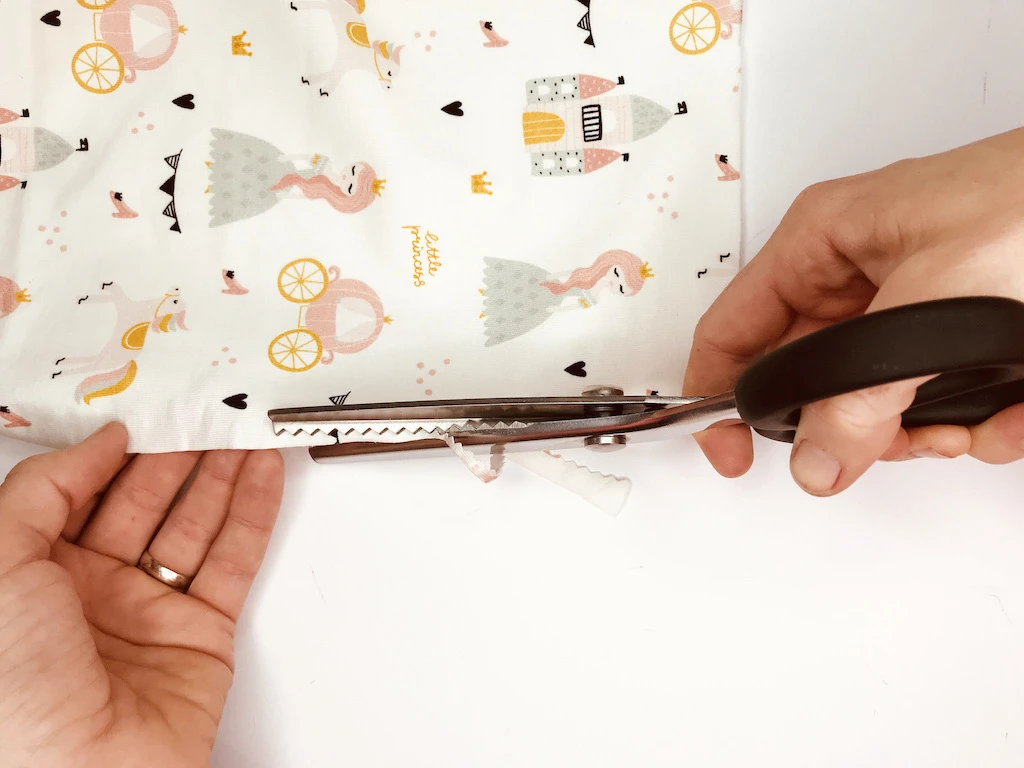 Cutting cotton jersey fabric with pinking shears.