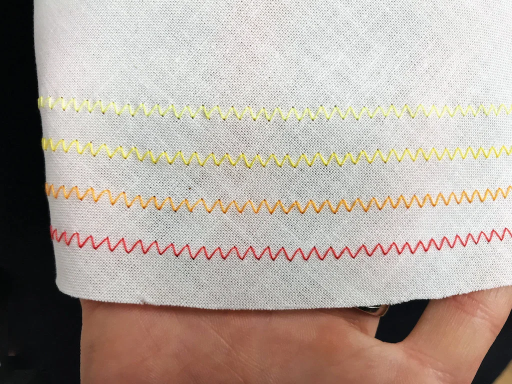 Colorful zig-zag stitches used to decorate the hem of a skirt.