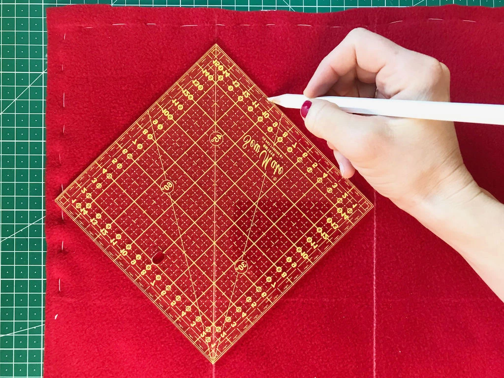 Drawing a pair of diagonal lines with a quilting ruler.