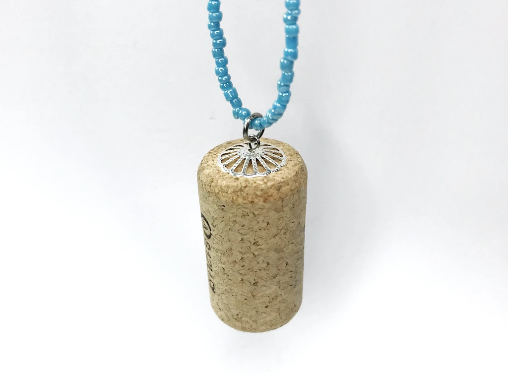 Bottle cork pendant hanging on a beaded necklace.