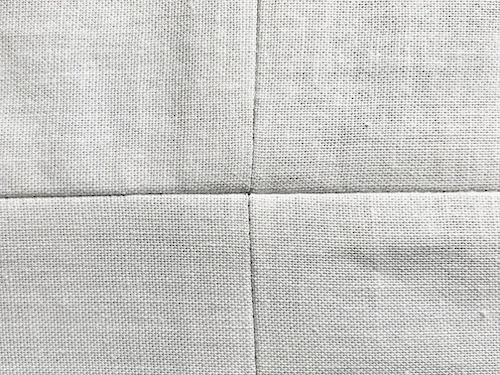Four pieces of fabric sewn together with perfectly matching seam allowances forming a cross.