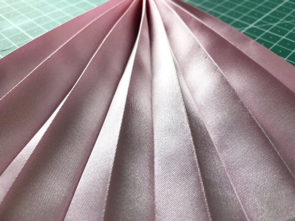Permanently pleated satin fabric. Permanent accordion pleats.