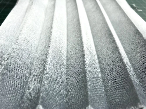 Permanently pleated crepe satin fabric sample. Permanent accordion pleats.