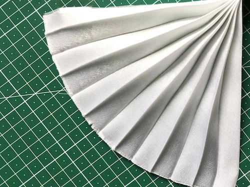 Permanently pleated crepe satin fabric sample. Permanent accordion pleats.
