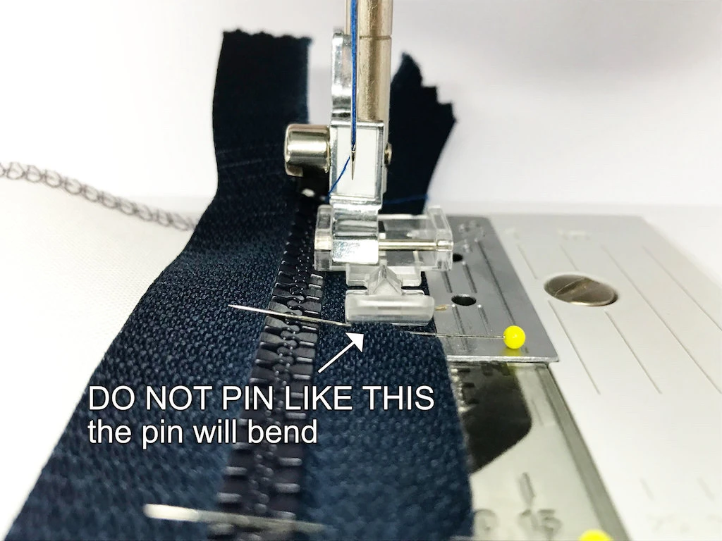 Pin perpendicular to zipper. This way the pin will bend.