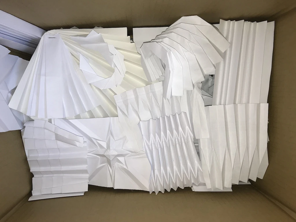Pleated paper samples in a cardboard box created during writing a book review about pleating.
