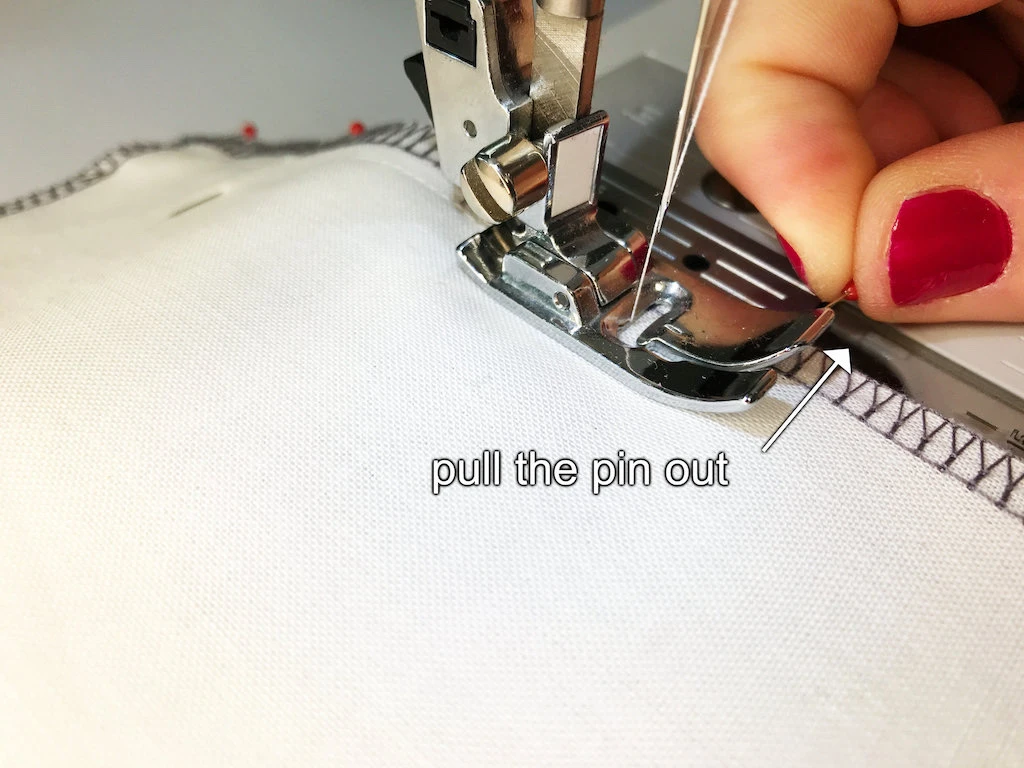 Pulling out a pin perpendicularly pinned into fabric.