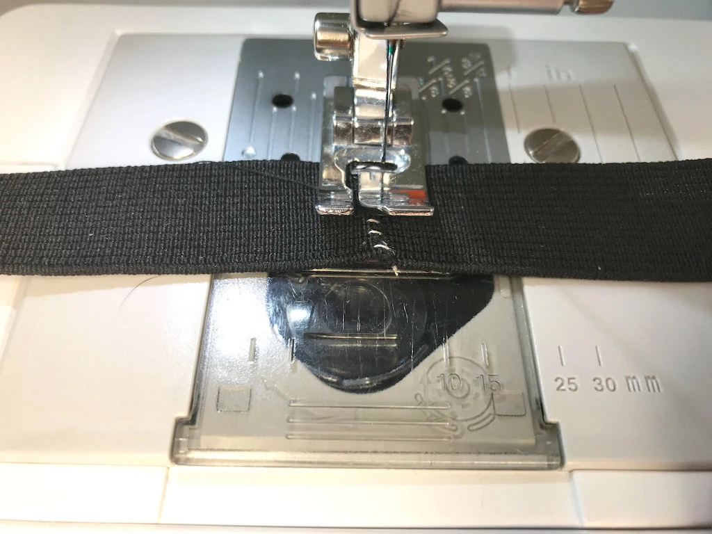 Sewing edges of an elastic waistband together using a dense zig zag stitch.