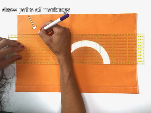Drawing pairs of markings on a piece of fabric.