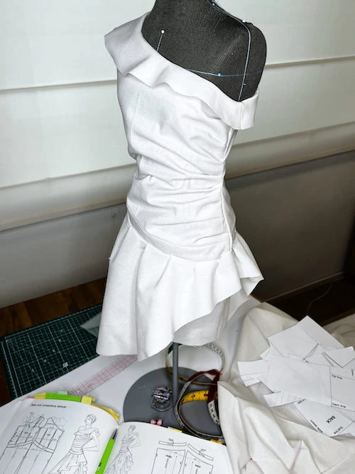 Asymmetric dress with flounces made of white cotton fabric.