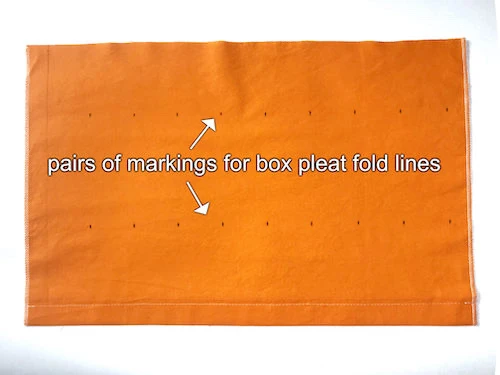 Drawn pairs of markings on a piece of fabric.