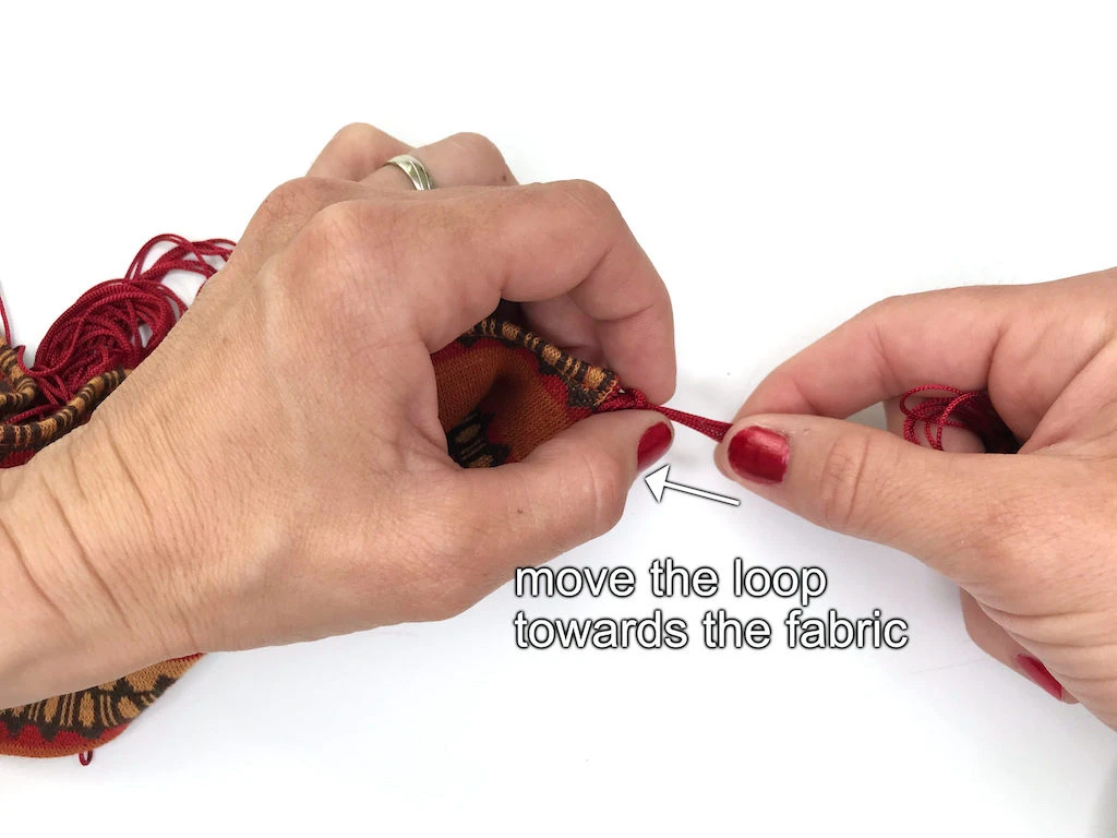 Moving looped fringe strings towards the headband fabric.