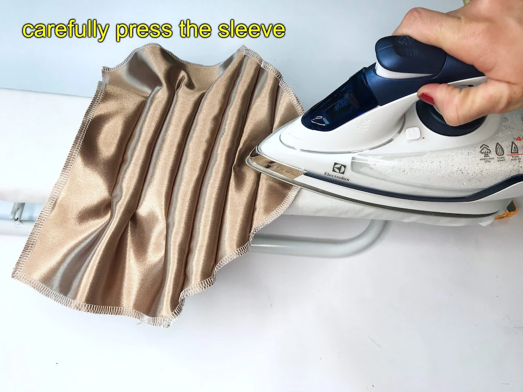 Pressing a beige set-in sleeve with tucks.