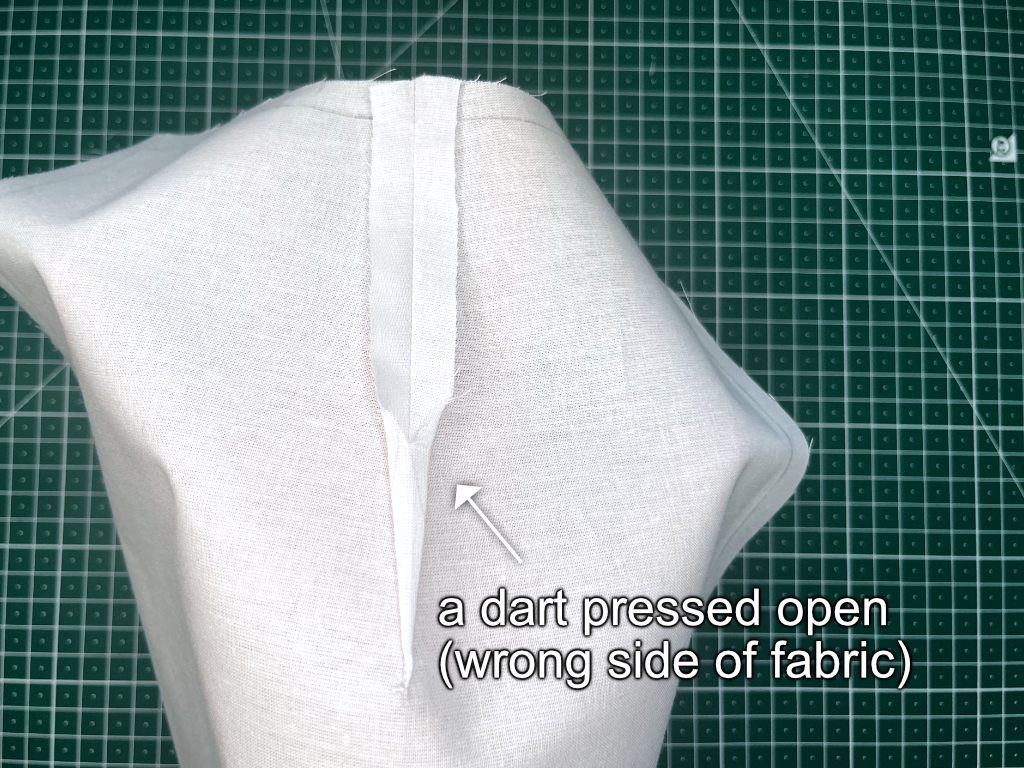 Darts in sewing patterns: dart with its bulk trimmed away pressed open.