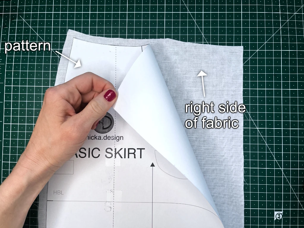 Positioning a sewing pattern on a right side of fabric before tracing a dart on it.