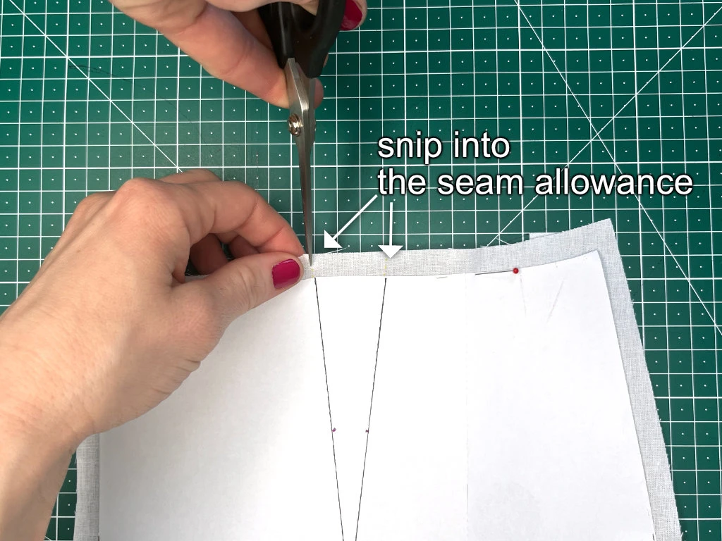 Snipping into the seam allowance of a pattern to indicate the end of dart legs.