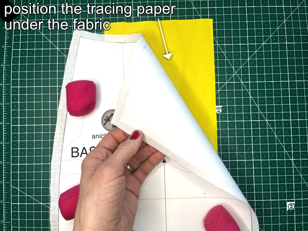 Positioning a tracing paper under a fabric (facing its wrong side) before transferring a dart to the fabric.