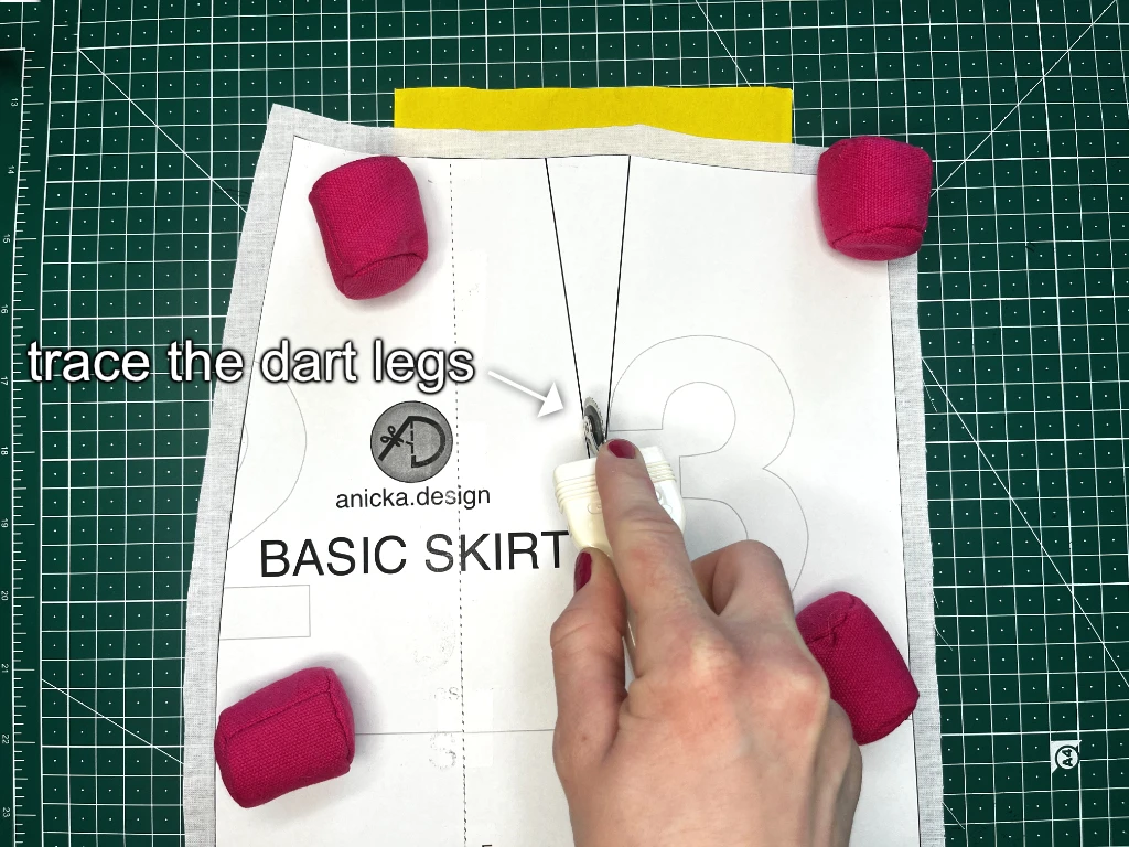Demonstrating how to trace darts in sewing patterns using a tracing wheel.